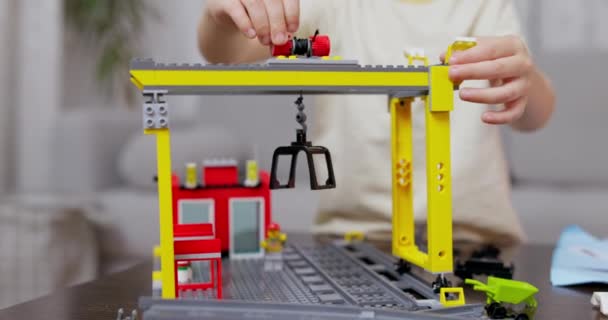 一个孩子的手从桌子上一个生机勃勃的连锁塑料套件上组装了一个建筑用起重机 高质量的4K镜头 — 图库视频影像