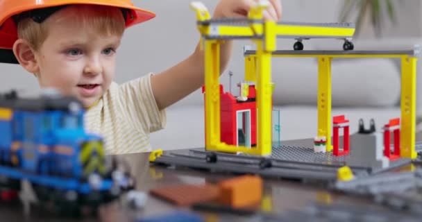 戴着硬礼帽的小男孩专注于建造一个玩具建筑工地 激发创造力和学习玩耍 高质量的4K镜头 — 图库视频影像