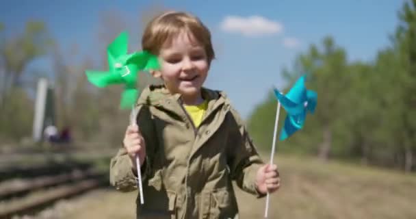 快乐的男孩带着蓝色和绿色的飞轮跑在外面 儿童户外活动的概念 高质量的4K镜头 — 图库视频影像