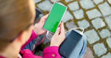 Pembe ceketli kişi telefonu şarj etmek için taşınabilir pil kullanıyor. Teknoloji ve hareketlilik kavramı. Yüksek kalite 4k görüntü