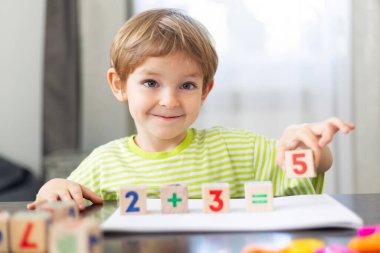 Gülümseyen çocuk temel matematiği renkli tahta bloklar kullanarak öğreniyor, erken eğitimi ve bilişsel gelişimi teşvik ediyor