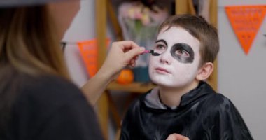 Cadılar Bayramı 'nda yüzü boyalı genç bir çocuk bir yetişkin tarafından uygulanacak. Yüksek kalite 4k görüntü