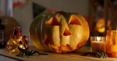 Parlayan mumlarla oyulmuş balkabağı ve masada ürkütücü süslemeler Cadılar Bayramı 'nın atmosferini yansıtıyor. Yüksek kalite 4k görüntü