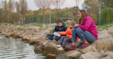 Dört kişilik bir aile, sonbaharın başlarında kayalar ve doğa ile çevrili bir göl kenarında huzurlu bir akşam geçirir. Yüksek kalite 4k görüntü
