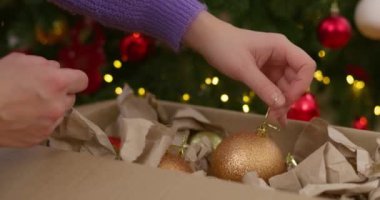 Madalyalı bir ağaca bronz bir Noel süsü takmak. Işıklı ve süslemeli festival sahnesi. Tatil sezonu ve Noel kutlaması konsepti. Yüksek kalite 4k görüntü