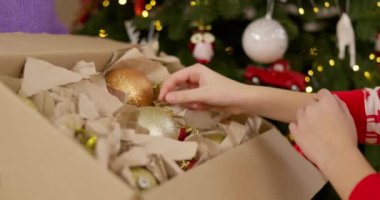 Bir anne ve oğulun Noel ağacını süslerken altın süsler asıp bayram mevsimini birlikte kutladıkları yakın plan. Yüksek kalite 4k görüntü