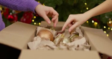 Bir anne ve çocuğun Noel mevsiminde güzel aydınlatılmış bir Noel ağacına süslemeler asması. Yüksek kalite 4k görüntü