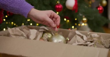 Bir insan Noel ağacını, bayram hazırlıkları sırasında bir kutudan çıkardığı süslemelerle süslüyor. Yüksek kalite 4k görüntü