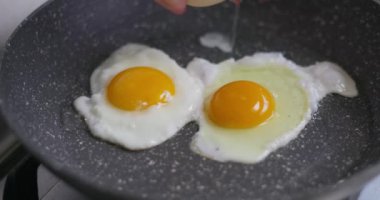 Üç güneşli tarafı yakın plan yumurta yapışmaz tavada kızartılıyor, pişirme sürecini detaylıca yakalıyor. Yüksek kalite 4k görüntü