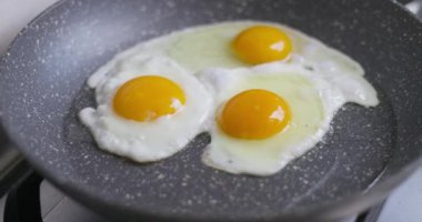 Güneşte pişmiş yumurtaları tavada pişiren, tavada yumurtayı kıran eli olan yumurtaları yakından çek. Yüksek kalite 4k görüntü