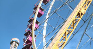 Dönme dolabın parlak metal çerçevesinin ve kulübelerinin açık mavi gökyüzüne doğru dönen yakın görüntüsü. Yüksek kalite 4k görüntü