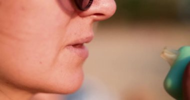 Genç bir kadın, altın saat boyunca plajın yakınında pastel renkli bir tüp kullanıyor ve rahat ve dengesiz bir yaz havası yaratıyor. Yüksek kalite 4k görüntü