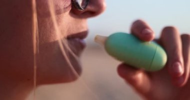 Kapalı devre elektronik bir cihaz kullanırken buhar üfleyerek dışarı çıkan bir insanın görüntüsü, rahatlama ve yaşam tarzı temalarını gösteriyor. Yüksek kalite 4k görüntü