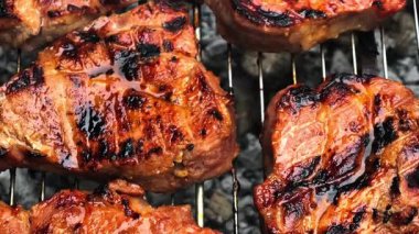 Izgarada ızgara yapan leziz bifteklerin yakın çekim videosu. Et ızgara izleriyle mükemmel bir şekilde kurutulmuş ve yaz barbeküsü için harika, sulu bir dokuya sahip..