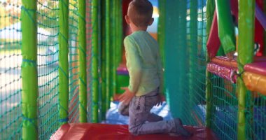 Genç bir çocuk, kapalı bir oyun parkındaki canlı, tünel içinde sürünmekten zevk alır. Sahne, oyun zamanının neşesini ve enerjisini güvenli ve renkli bir ortamda yakalıyor..