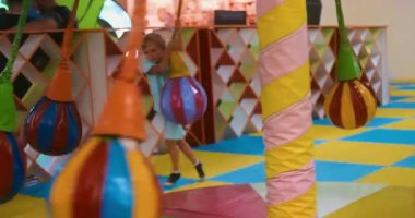 Çocuklar renkli asılı topların ve döşemelerin yer değiştirdiği hareketli bir oyun bahçesinin keyfini çıkarıyorlar. Neşeli ortam eğlence ve güvenlik için tasarlandı, aktif oyun için teşvik edici..