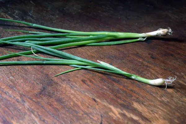 Ahşap zemin üzerinde taze yeşil soğanlar