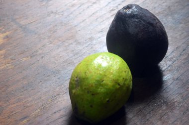 Ahşap arka planda iki yeşil avokado..