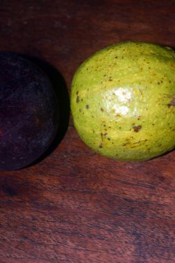 Tahta zemin üzerinde olgun, taze kırmızı ve siyah mango yarımları. Kapat..