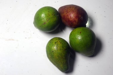 Beyaz arka planda yeşil, sarı ve kırmızı avokado meyvesi.