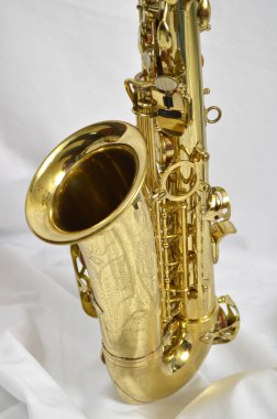 Beyaz arka planda beyaz saplı altın bir saksafonun dikey çekimi.