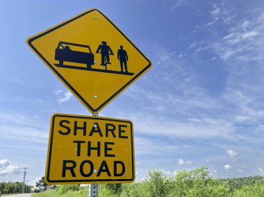 Sarı yol tabelası sürücülere yolu bisikletçiler ve yayalarla paylaşmalarını ve yol güvenliğini desteklemelerini hatırlatıyor