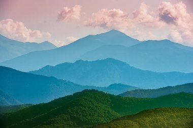 Mavi dağları ve pembe gökyüzü olan güzel bir manzara.