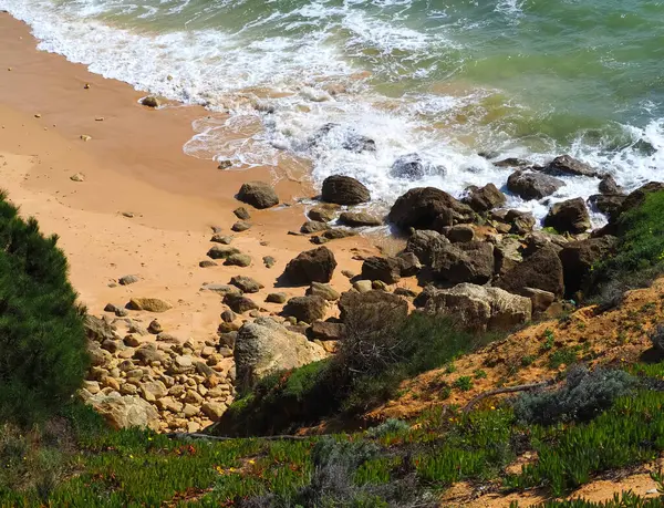 Kayalıkları ve kumları olan güzel bir Algarve sahilinde deniz sörfü.