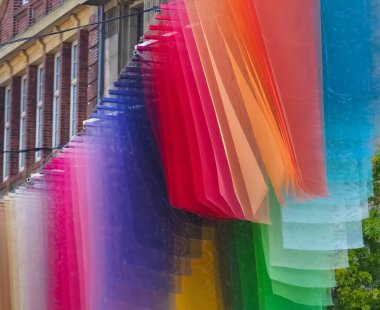 Gökkuşağı renginde bayraklar Almanya 'nın bir şehrinde rüzgarda dalgalanıyor.