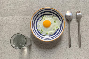Gri arka plan görünümlü, yumurta ve bir fincan maden suyu ile kahvaltı.