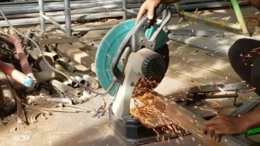 Arka bahçesinde kıvılcımlar olan ağır çekimde metal kesme makinesi, Metal 'de elektrikli testere kıvılcımları, kesme makinesiyle çeliği kesen adam.