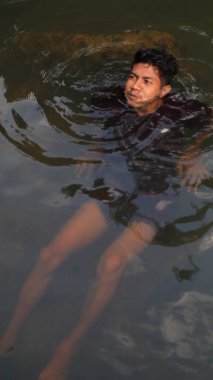 Bulanık suda yüzen adam, su altında görülebilir bacaklar, siyah bez.