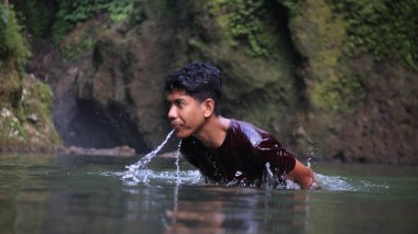 Dağ deresinden su içen adam