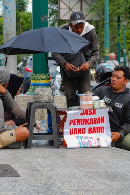 Yogyakarta, Endonezya - 8 Mayıs 2025: Yogyakarta şehrinin yol kenarında elle para değişimi hizmetleri, Endonezya 'da önemli anlarda yeni para alışverişi hizmetleri