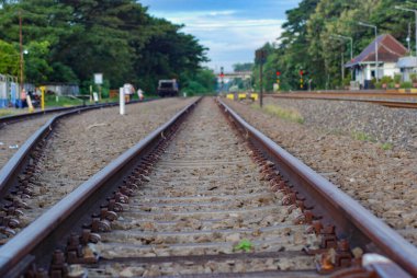 Düz demiryolu hattının soyut arka planı, çakıllı demiryolu, kenarında büyük ağaçlar olan düz bir yol.