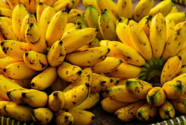 Bambu sepetlerinin üzerinde taze muzlar, geleneksel bir pazarda satılıyor, organik taze meyveler, yakın plan.