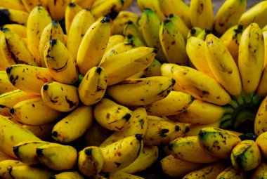 Bambu sepetlerinin üzerinde taze muzlar, geleneksel bir pazarda satılıyor, organik taze meyveler, yakın plan.