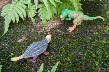 Ormanda savaşmak isteyen dinozor heykellerinin oyuncak sahnesi.