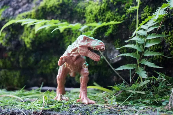 photos of toy dinosaur sculptures with jungle scenery and rocky nature outdoor