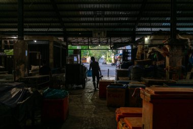 İtme çarkını tutan bir adamın silüeti dışarıdaki balık kutusunu dükkanına taşıyor. Çok çalışan biri.