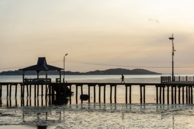Liman köprüsünün manzarası ve yürüyen bir adam. Akşamın güzel günbatımı, su çok sakin ve berrak.