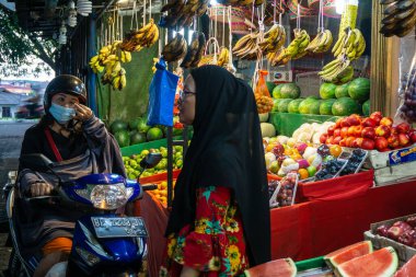 Tanjungpinang, Endonezya - 15 Aralık 2024: Meyve almak isteyen müşterilere meyve satan esnaflar