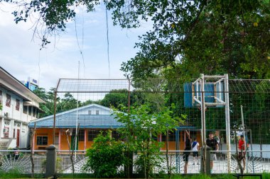 Tanjungpinang, Indonesia - December 21, 2024: a group of young people playing and practicing basketball on the school grounds clipart