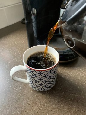 Sıcak filtre kahve bir ev mutfağında kupanın içine dökülüyor.