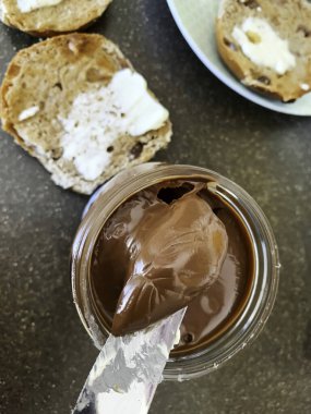 Sıcak haç ekmeğine sürülmek üzere çikolata dolu bir bıçak. Yüksek kalite fotoğraf