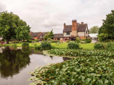 Acton Trussell, UK - Saturday 6th July 2024: Looking across the lake toward the bar area of the Moat House Hotel. High quality photo clipart