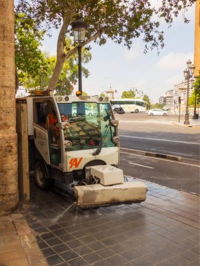 Valencia, İspanya - 23 Ağustos 2024 Cuma günü mekanik bir sokak temizleyicisi kaldırımı dezenfektanla yıkıyor. Yüksek kalite fotoğraf