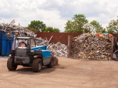 Scrap brass separated in a bay ready to be loaded into a container for export. Loading shovel in scrap yard. High quality photo clipart