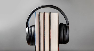 Modern black headphones on stack of books. The concept of audio books listening. Modern technologies. Digital library.