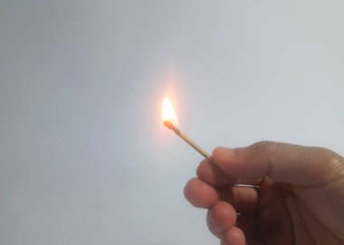 Elinde yanan bir kibrit tutan bir adam.